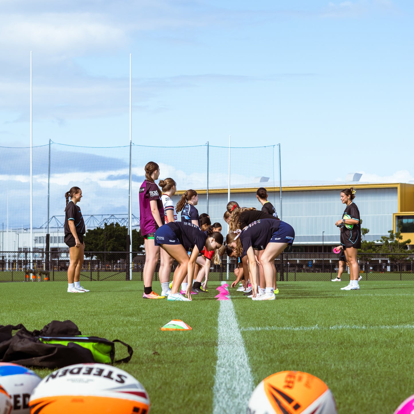 Group of young rugby league players on the sideline picking up cones during game