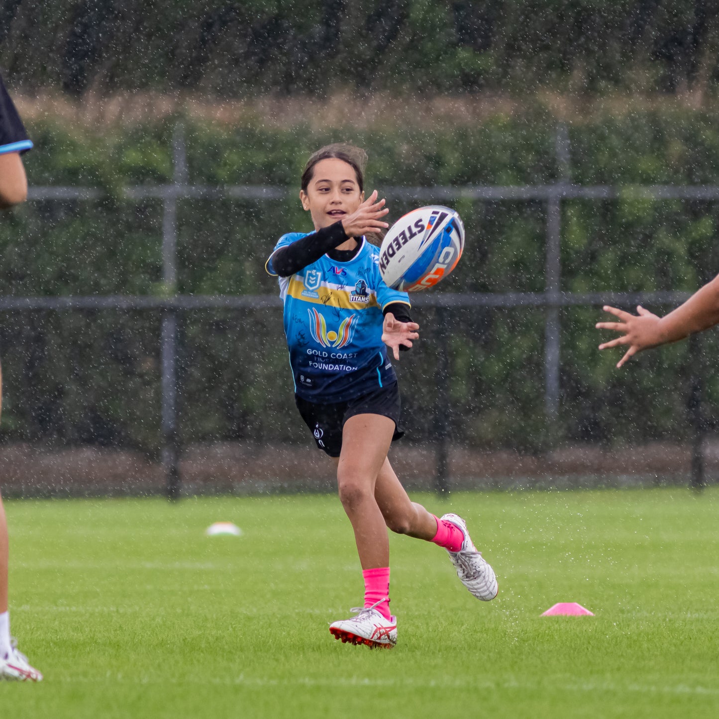 Young female athlete passing a football in the rain