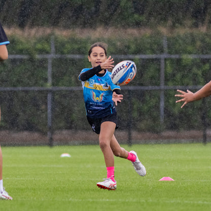 Young female athlete passing a football in the rain